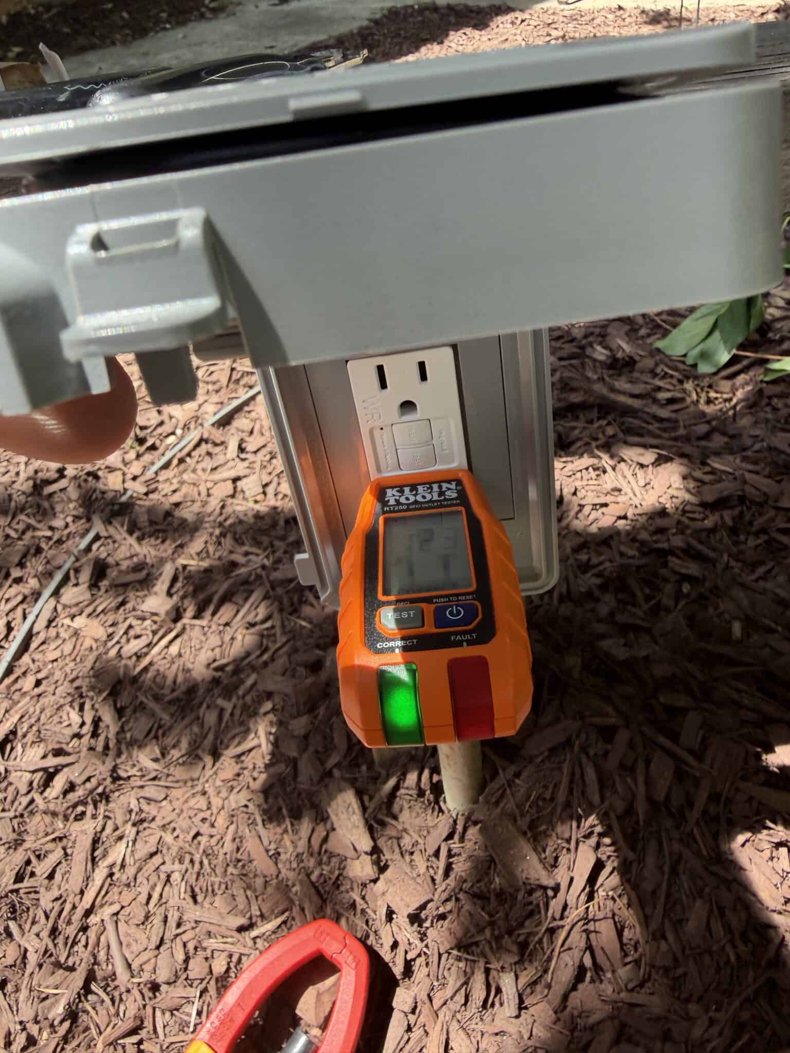 Testing an outdoor electrical outlet with a digital multimeter.